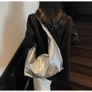 Sac hobo métallisé argenté à texture souple présenté par un mannequin dans un escalier