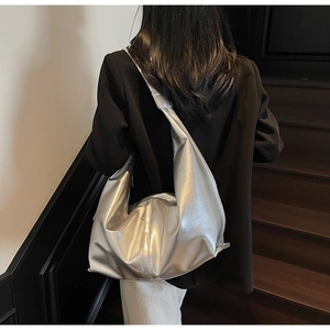 Détail d'un grand sac hobo argenté métallisé avec une large bandoulière sur modèle