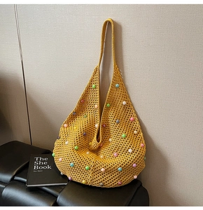 Detailed close-up of yellow knit crochet beach bag with colorful pearl embellishments