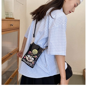 Détail d'un mini sac bandoulière en cuir verni noir avec motif fille cartoon et mimi