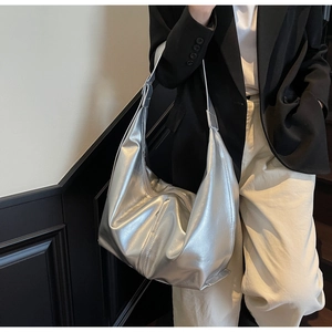 Sac hobo métallisé argenté minimaliste avec large bandoulière porté par un mannequin