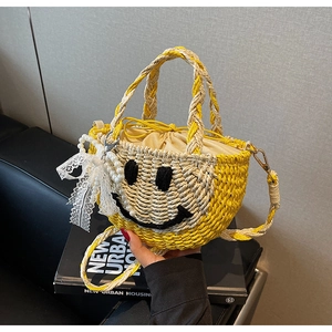Detailed view of handmade woven straw bag with smiling face, pearl charm and lace bow