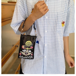Détail de la pochette téléphone à paillettes noires avec broderie cartoon