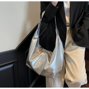 Détail d'un grand sac à bandoulière argenté avec texture métallisée froissée sur modèle