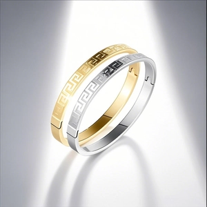 Detail of gold and silver stainless steel bangles with Greek Key pattern and mirror finish