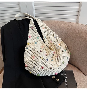 Close-up of knit hollow-out beach bag with colorful pearls on black blazer