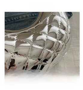 Macro detail of silver mirror finish acrylic bag with quilted diamond pattern and studs