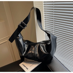 Gros plan détaillé d'un sac à bandoulière noir brillant avec large sangle et boucle argent