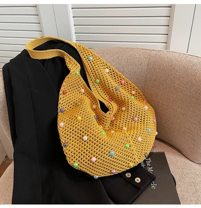 Close-up of yellow crochet tote bag with colorful pearl beads on a beige texture sofa