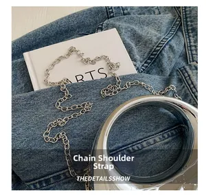 Detailed close-up of a silver mirror acrylic handbag with a metal chain shoulder strap