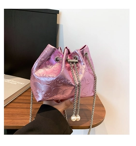 Close-up of pink metallic bucket bag with skull embossing and pearl chain details