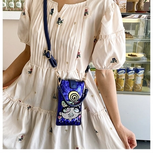 Détail du sac bandoulière à paillettes bleues avec visage de dessin animé sur mannequin