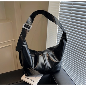 Détail du sac hobo noir brillant avec bandoulière réglable et boucle carrée argentée