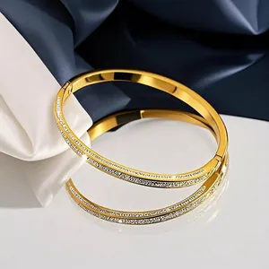 Luxuriöses Set aus goldenen Edelstahlarmreifen mit Ätztextur auf feinem Seidenhintergrund