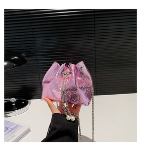 Detailed view of pink metallic bucket bag featuring skull embossing and pearl drawstring