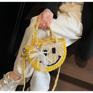Detail of handmade straw bag with smiley face embroidery and lace ribbons in soft focus