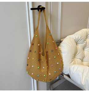 Detail of a ginger yellow crochet hobo bag with colorful beads for beach vacations