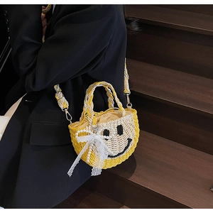 Detail of hand-woven straw bag with smiley face pattern and pearl lace bow accessory