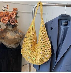 Detail of yellow knit crochet shoulder bag with colorful pearls on a stylish background