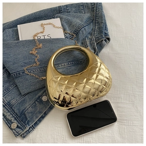 Detail of gold crescent handbag with diamond pattern texture and round hollow handle