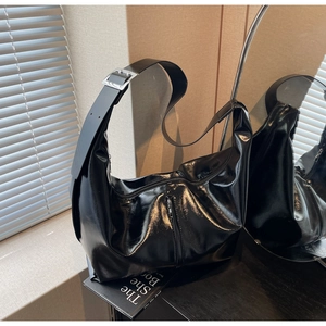 Détail du sac bandoulière en cuir PU noir brillant avec large sangle et boucle argentée