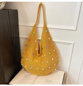 Detail of yellow knit hobo bag with colorful pearls and crochet hollow texture