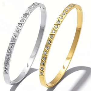 Detailed view of silver and gold stainless steel bangles with geometric diamond inlay