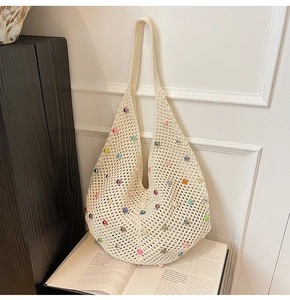 Detail of crochet beach bag with colorful beads on ivory knit net mesh fabric