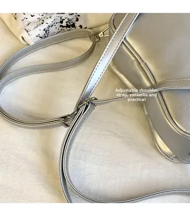 Gros plan sur la bandoulière réglable et la boucle métallique argentée du sac brillant