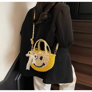 Detail of yellow woven bucket bag with smiley face pattern and lace bow accessory