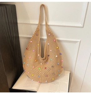 Detail of beige crochet beach bag featuring colorful pearl beads on a woven surface