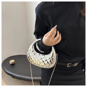 Detail of silver metallic crescent bag featuring quilted texture and glossy mirror finish
