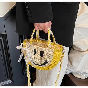 Detail of straw woven bag with black smiley face embroidery and pearl lace charm