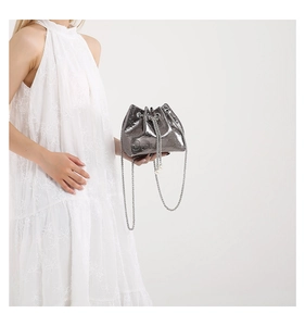Detail of silver bucket bag with skull embossed texture and elegant pearl chain