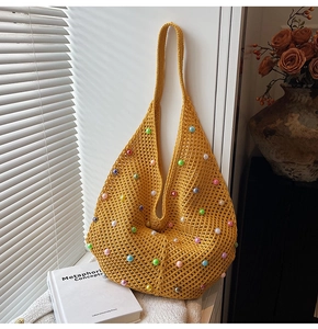 Close-up of yellow knit tote bag featuring colorful pearl bead accents and hollow texture