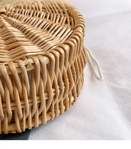 Detail of hand-woven round bamboo bag with tight herringbone pattern and white drawstring