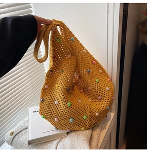 Detail of yellow knit tote bag featuring colorful pearl beads and crochet texture