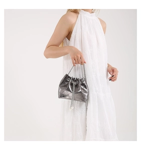Detail of silver bucket bag with skull embossing, metal chain, and pearl drawstrings
