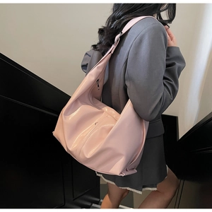 Gros plan d'un sac hobo rose brillant porté par un mannequin pour un look chic et moderne