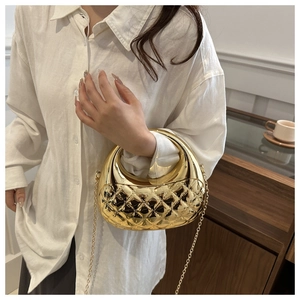 Detail of a gold quilted acrylic evening bag with top handle and fine chain strap
