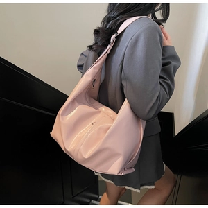 Détail du sac cabas en cuir verni rose avec large bandoulière porté par un mannequin