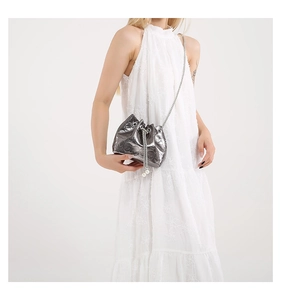 Detail of silver bucket bag featuring skull relief patterns and pearl chain accents