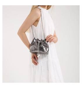 Detail of silver bucket bag featuring skull relief patterns and pearl chain strap
