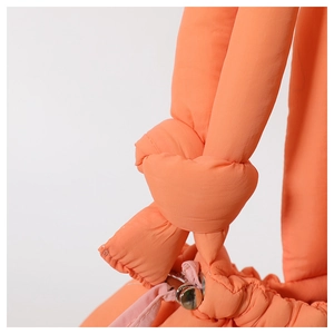 Close-up of bright orange quilted bag showing knotted strap and pink drawstring detail