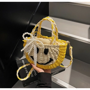 Detail of straw woven handbag with black smiley face pattern and lace bow decor