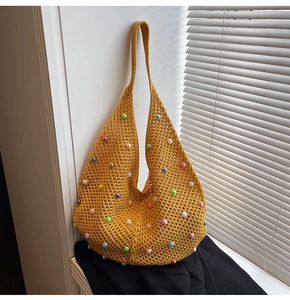 Detail of yellow crochet hobo bag with colorful pearl accents and woven mesh texture