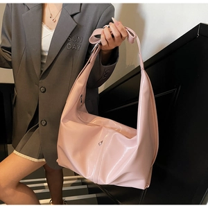 Détail du sac à bandoulière rose brillant montrant la texture lisse sur le modèle