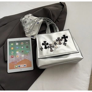 Dettaglio borsa in pelle metallizzata argento con toppe a croce e design con patta
