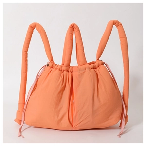 Detail view of orange quilted puffer bag with drawstring closure and glossy nylon texture
