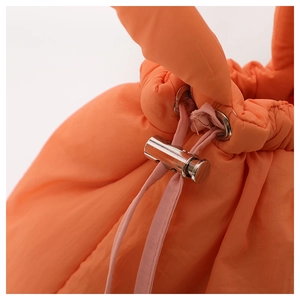 Close-up of orange puffer bag with silver metal buckle and soft drawstring detail